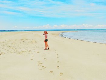 Woman standing on beach against sky