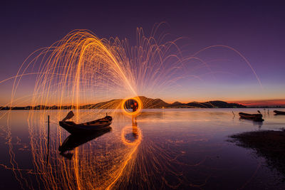 Firework display over sea against sky at night