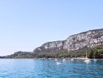 Scenic view of sea and mountains against clear blue sky
