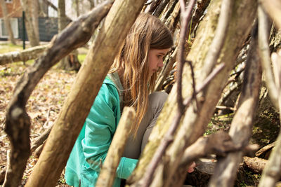 Low angle view of woman standing by tree trunk