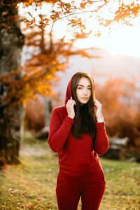 Young woman standing against trees during autumn