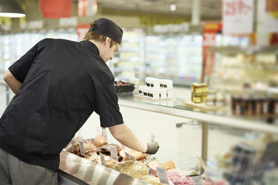 Rear view of man in supermarket working at deli counter