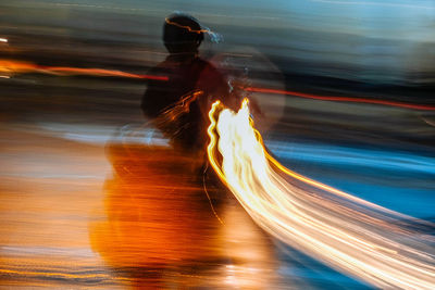 Blurred motion of woman light trails on road at night