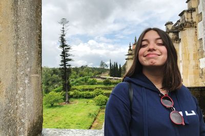 Portrait of a smiling young woman standing against trees