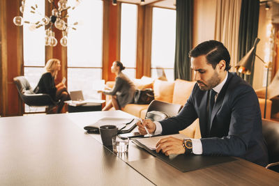 Mid adult lawyer reading documents while female colleagues discussing in background