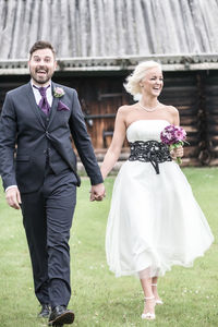 Portrait of smiling groom with bride walking in yard