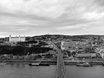 Bridge over river in city against cloudy sky