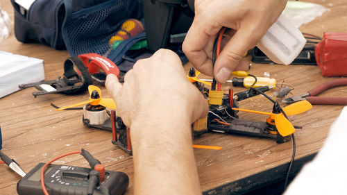 Cropped hands of man repairing quadcopter at workshop