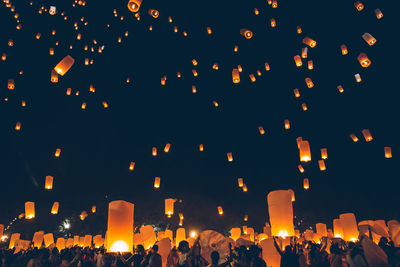 Group of people at illuminated lanterns at night