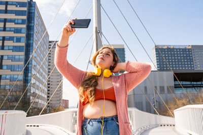 Young woman taking selfie on footbridge