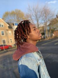 Side view of young man standing on road in the city