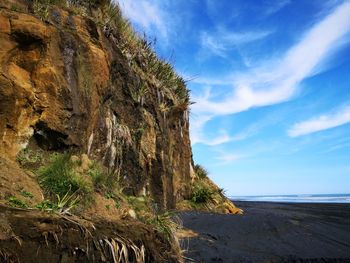 Scenic view of rocks by sea against sky