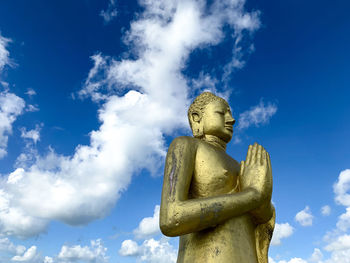 Low angle view of buddha statue against blue sky