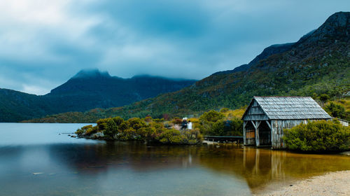 House by lake and mountains against sky