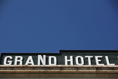 Low angle view of text on building against clear blue sky