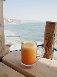 Close-up of coffee on table by sea against sky
