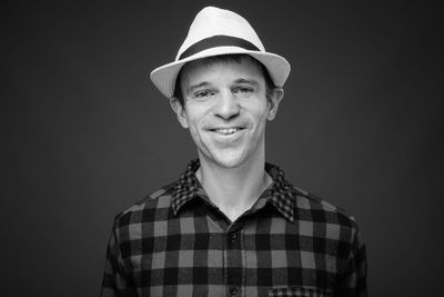 Portrait of smiling man standing against black background