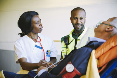 Doctor talking to paramedic while treating mature businessman on hospital gurney