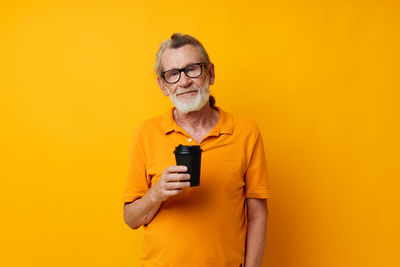 Young woman using mobile phone against yellow background