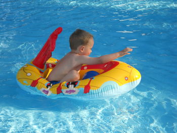 Side view of boy on inflatable toy raft in swimming pool