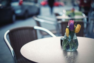Colorful tulip flowers in vase on table at sidewalk cafe