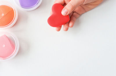 A child holds a heart made of plasticine. white wooden background with copy space.