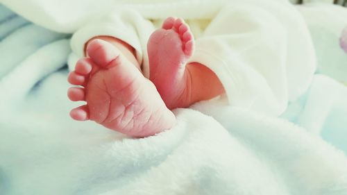 Low section of newborn lying on bed