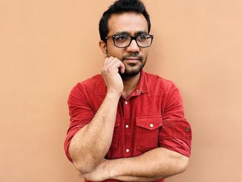 Young man wearing sunglasses while standing against yellow background