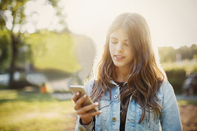 Teenager using smart phone while standing at park