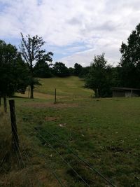 Scenic view of grassy field against cloudy sky