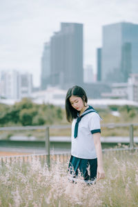 Young woman standing amidst plants on field