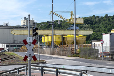 A large port crane on rails standing on the loading yard, visible yellow silos.