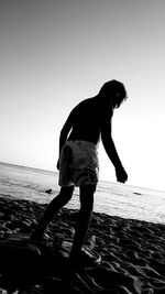 Full length of silhouette man standing on beach against clear sky