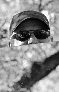 Close-up portrait of man holding mirror while standing by plants