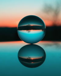 Close-up of crystal ball on water at sunset