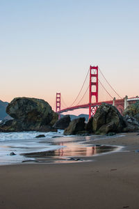 Suspension bridge over sea against clear sky