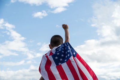 Low angle view of men flag against sky