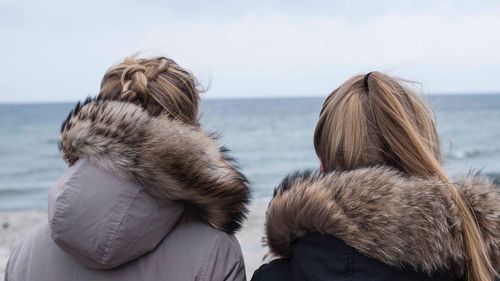 Rear view of girl looking at sea shore against sky