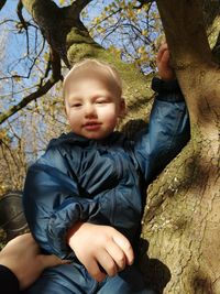 Full length of cute boy sitting on tree