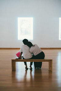 Rear view of couple sitting on hardwood floor