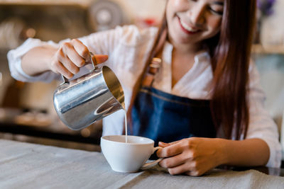 Midsection of woman having coffee in cafe