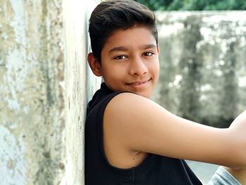 Side view portrait of smiling boy sitting outdoors