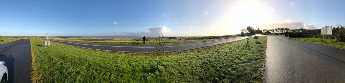 Panoramic shot of road amidst field against sky