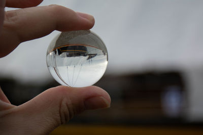 Close-up of person holding crystal ball with boat reflection 