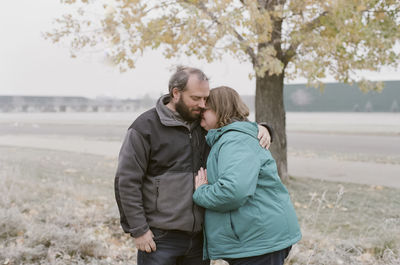 Mature couple wearing warm clothing embracing on field