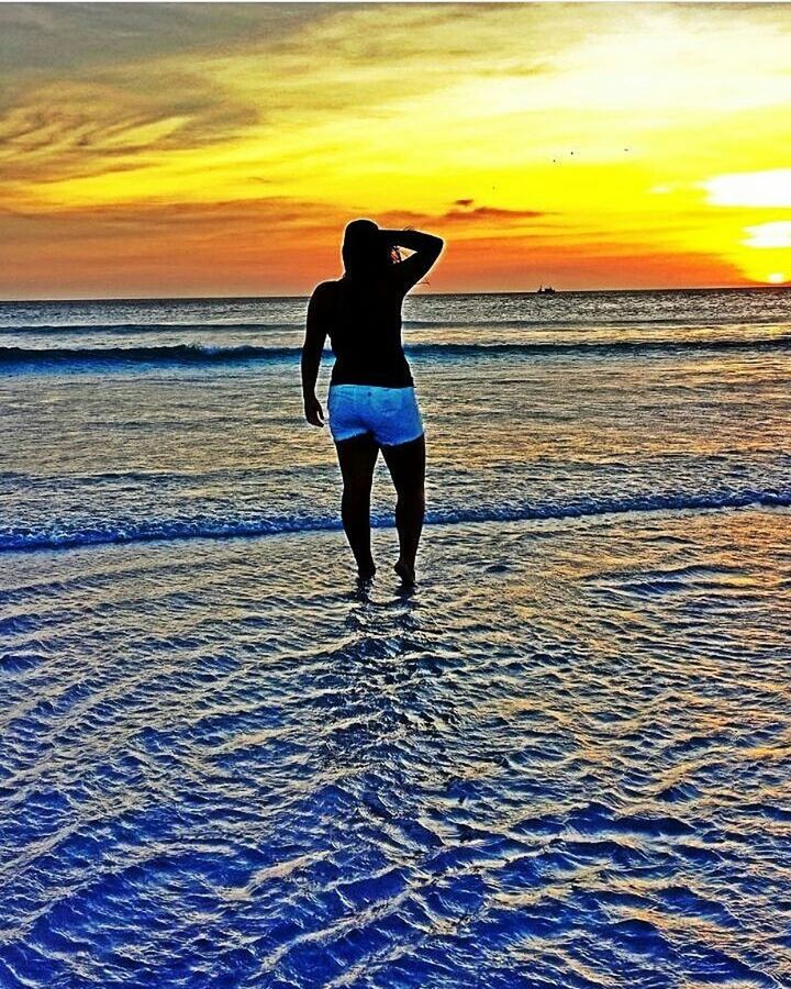 FULL LENGTH OF WOMAN STANDING AT BEACH DURING SUNSET