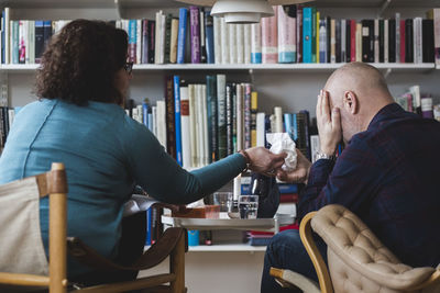 Female therapist giving tissue to crying patient at home office