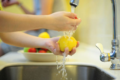 Cropped hand washing lemon in kitchen at home