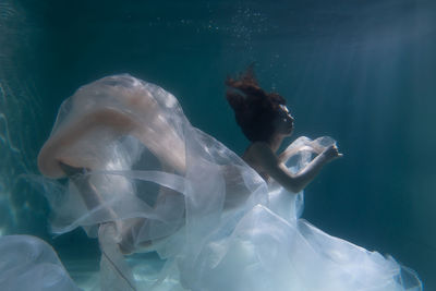 Woman with curtain swimming in pool