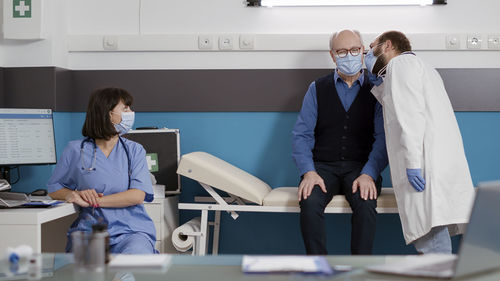 Doctor wearing mask examining patient in clinic